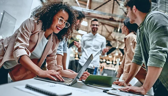 Group of business professionals for a growing business standing together over a table having a exciting conversation.
