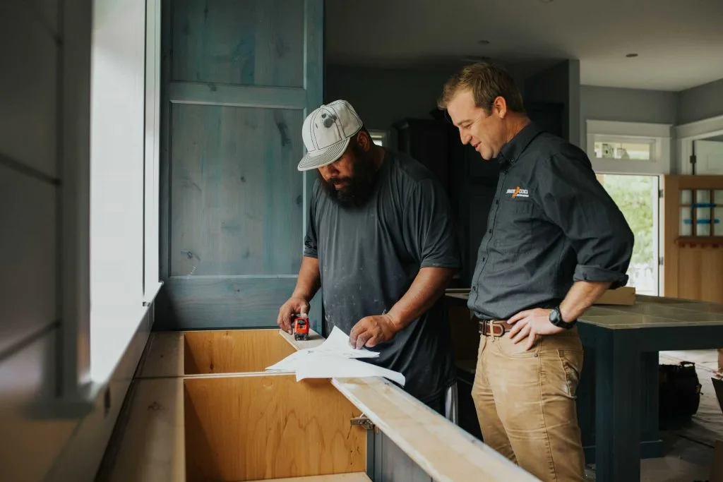 Two men standing and discussing construction inside of a home renovation.