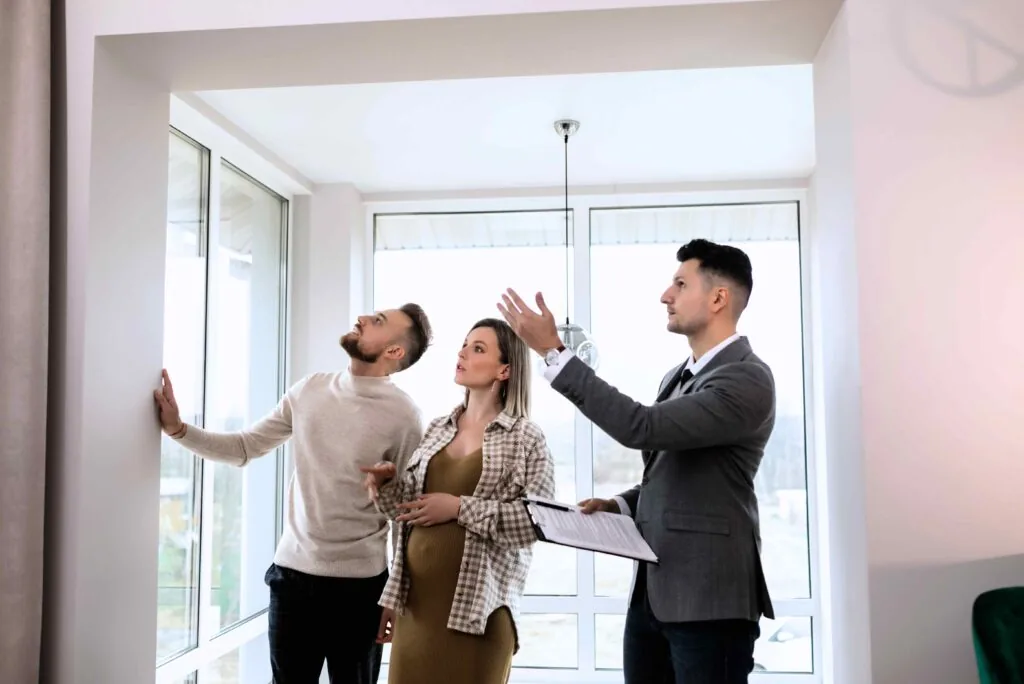 A real estate professional standing and having a conversation with potential homeowners.